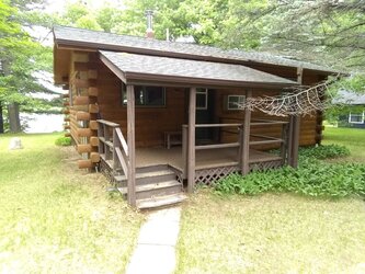 Ray's family cabin in Wisconsin. Small brown log cabin with front porch